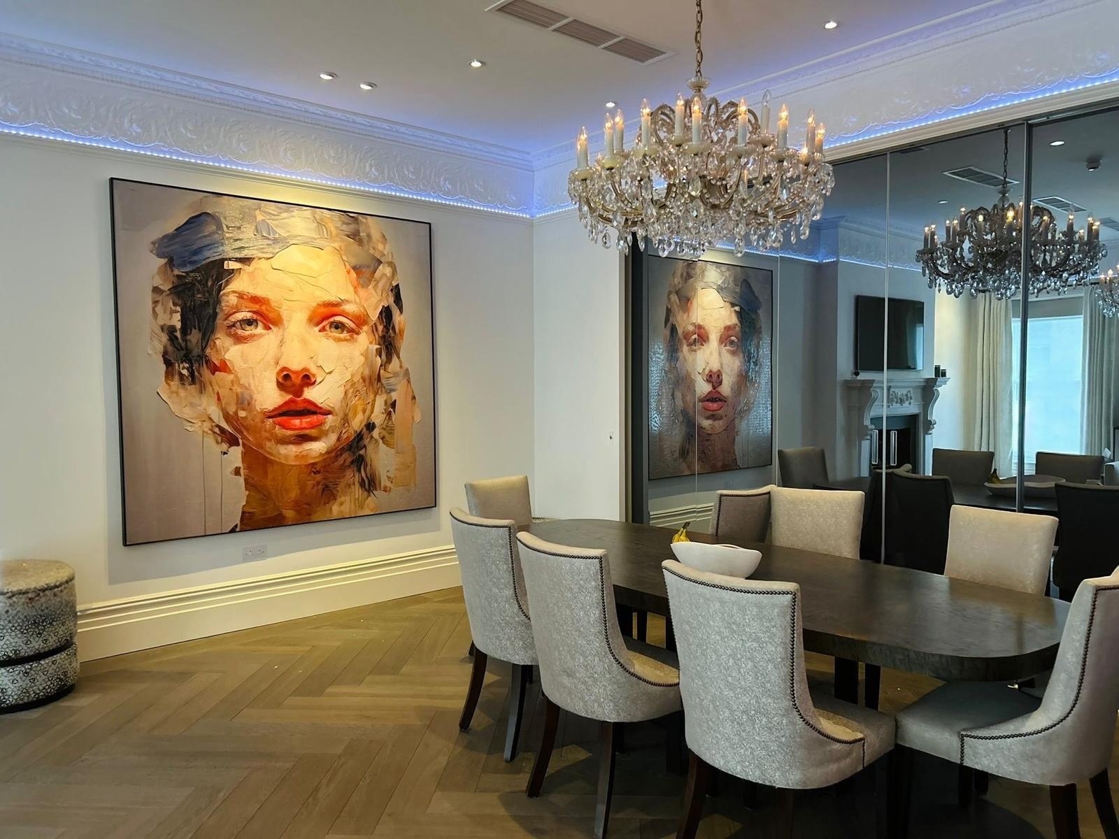 A large contemporary portrait painting hanging in an elegant London dining room with a crystal chandelier and mirrored wall